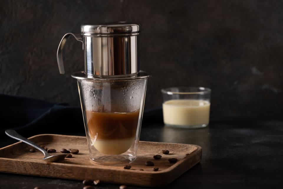 Víetnamskt kaffi lekur úr phin-síu ofan í glas með dósamjólk.