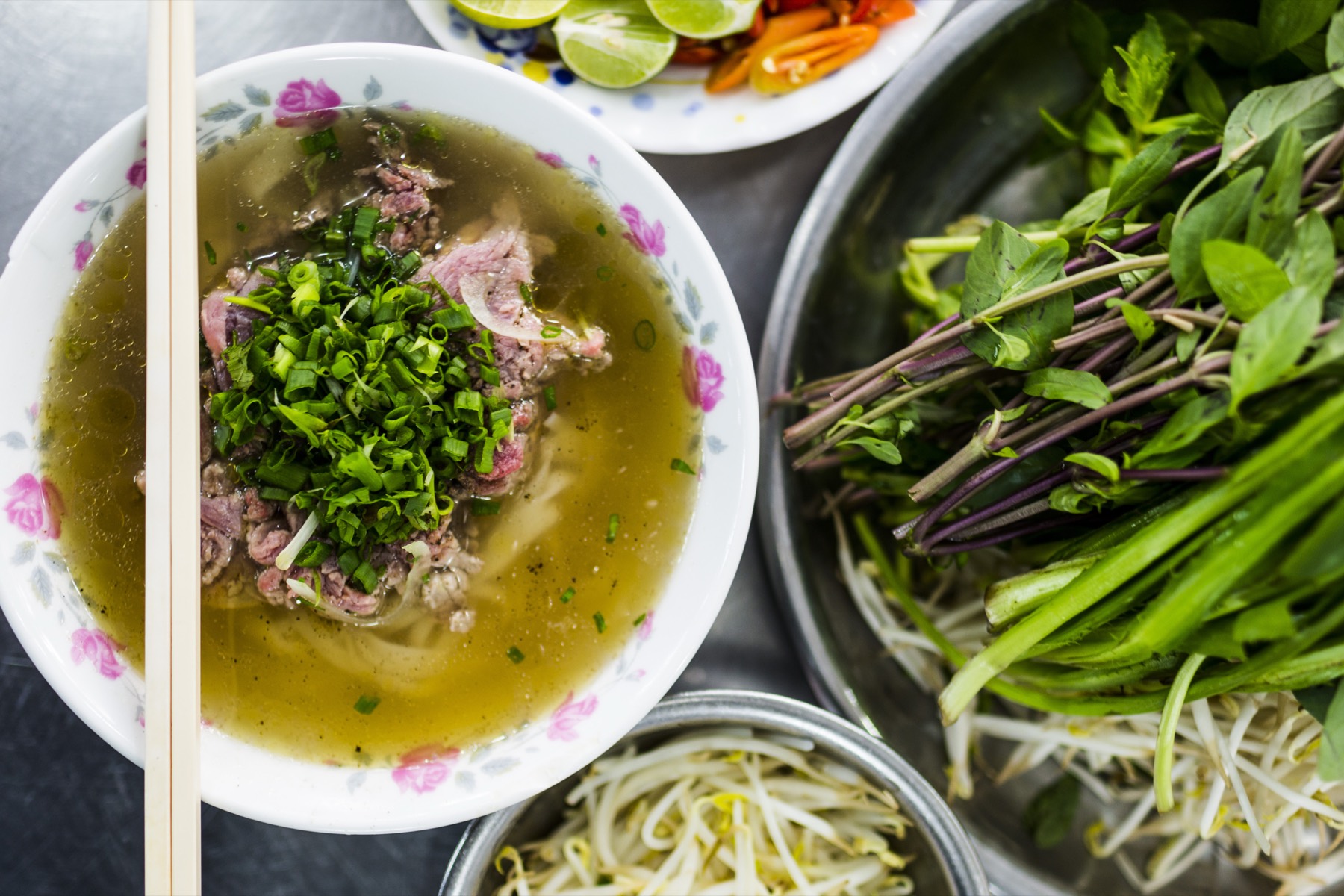 Phở með nautakjöti séð ofan frá ásamt kryddjurtum.